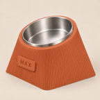 Contour Tilt custom height dog bowl in Terracotta, with a tilted stainless steel bowl, fine vertical grooves and MAX example nameplate.